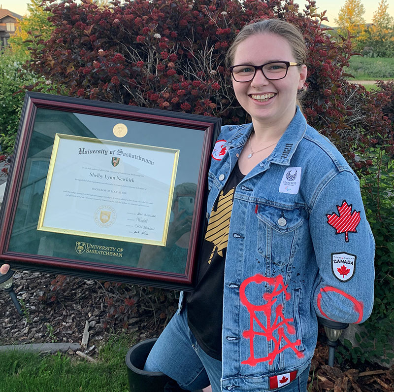 New Bachelor of Education graduate Shelby Newkirk with her framed USask degree and her Tokyo Paralympics jacket. (Photo: Submitted) 