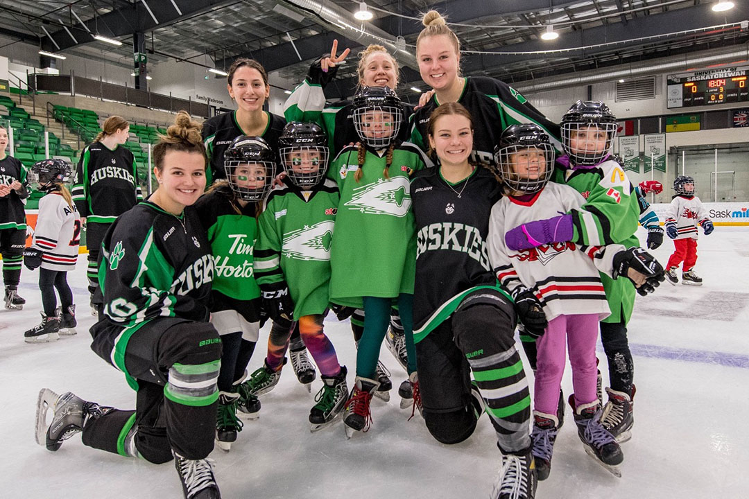 Members of the Huskies women's hockey team gather on ice with fans at Merlis Belsher Place. 