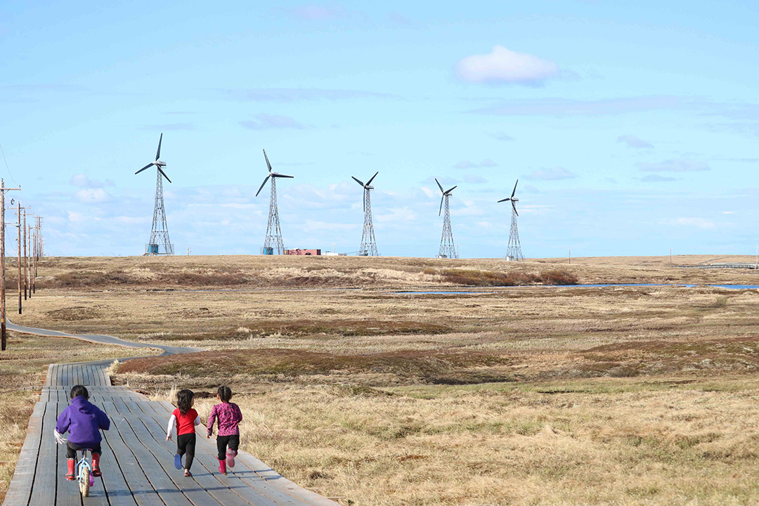 Children run along the boardwalk in the remote northern community of Kongiganak on Alaska’s Yukon Kuskokwim Delta where wind energy combined with a battery storage system provides up to 100 per cent of the community’s electric needs. (Photo: Amanda Byrd)