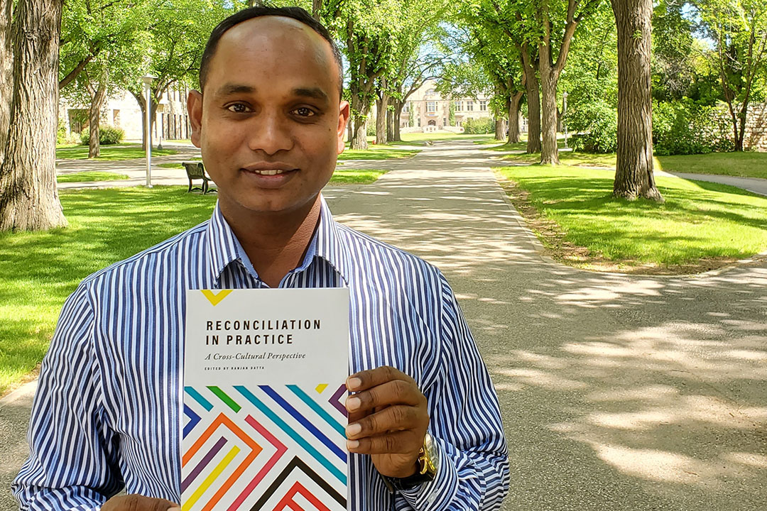 University of Saskatchewan (USask) alumnus Dr. Ranjan Datta (PhD) with his new book, Reconciliation in Practice: A Cross-Cultural Perspective. (Photo: Megan Evans)