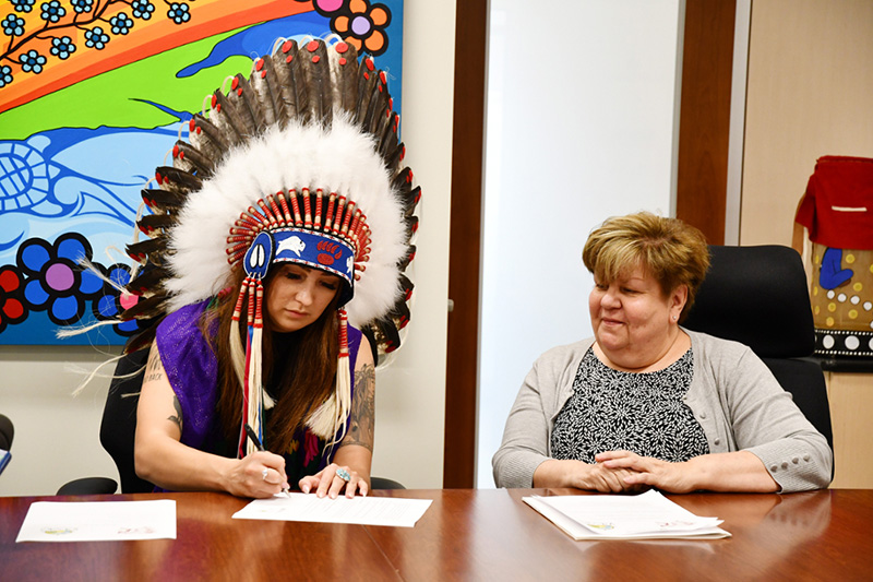 FSIN Third Vice Chief Aly Bear signs an MOU with Pewaseskwan as Alexandra King looks on. The MOU, signed June 24, 2022, will foster stronger research ties between Pewaseskwan and the Saskatchewan First Nations Women’s Commission (SFNWC). (Photo by Sarah MacDonald) 