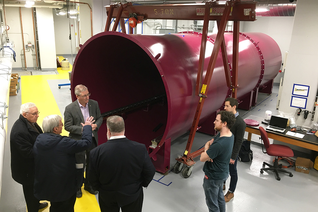 McMaster researcher Bruce Gaulin shows board members Bill Stirling and Peter MacKinnon, and Fedoruk Centre Executive Director John Root the magenta detector tank at the MacSANS instrument where a custom-built neutron detector will be installed  