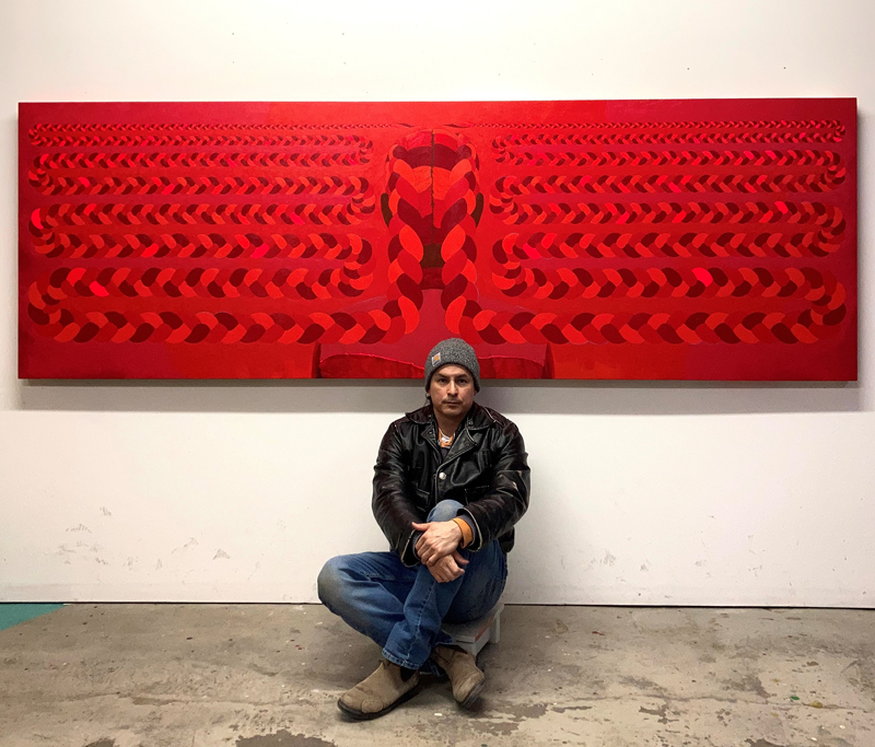 Wally Dion (BFA'04) is pictured in his studio with red braids, 2022. (Photographic image courtesy of the artist.)