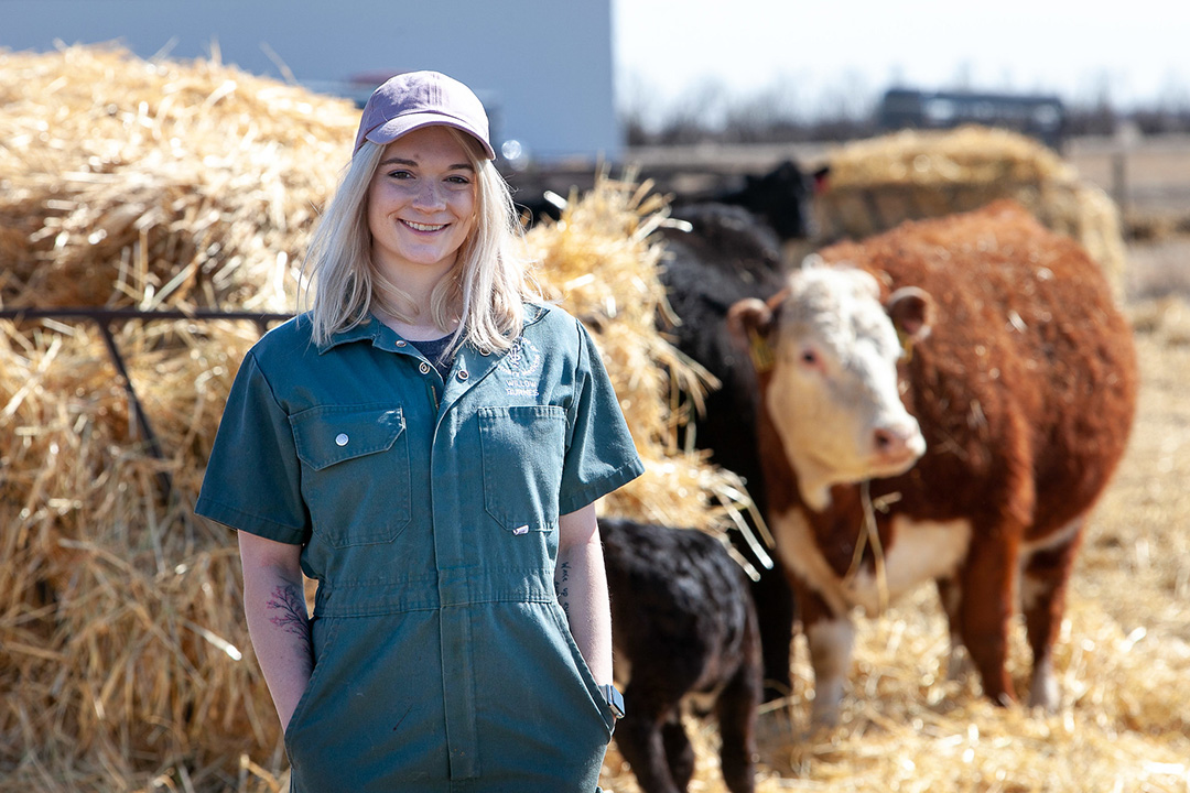 A veterinary medicine student poses with cows in background. 