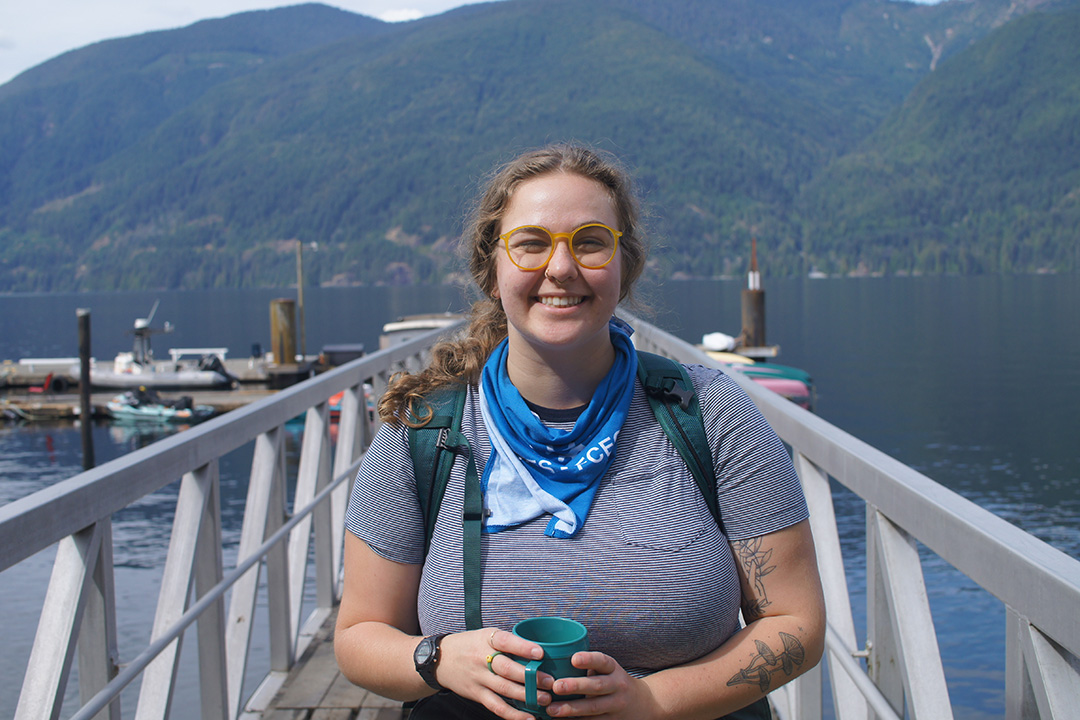 Headshot of Shanleigh McKeown, who is standing in front of a scenic lake amidst mountains. 