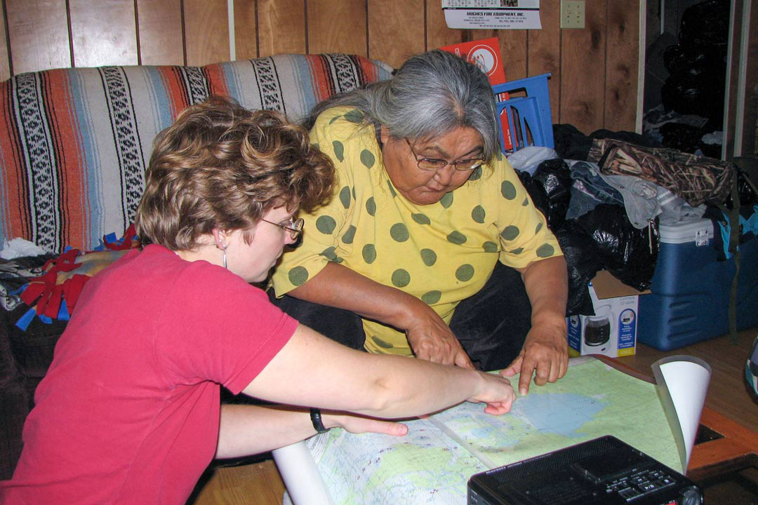 Dr. Olga Lovick (PhD) reviews Upper Tanana place names with the late Cora H. David, an Elder, storyteller and teacher, at David’s home in Tetlin, Alaska, in 2009. 