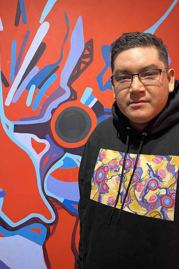 Indigenous USask graduate Brody Burns is seen in front of one of the paintings that was featured in his MFA exhibition at the Snelgrove Gallery this summer. 