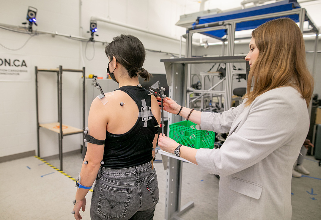 Dr. Angelica Lang demonstrates the use of a device for scapula motion tracking on student Lauryn Campbell. (Photo: Christina Weese)
