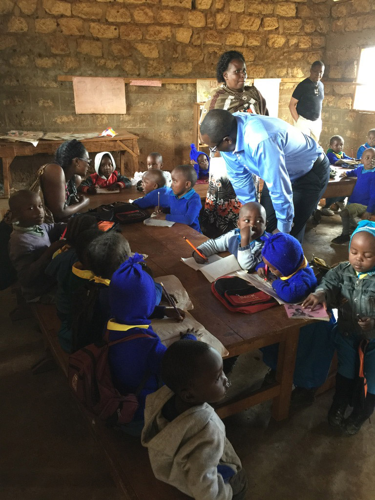 From right, Dr. George Mutwiri (DVM, PhD) and his children George Jr. and Vanessa, as well as Gitonga (at left) present soccer balls to George’s old school in Nkabune Village in Kenya in 2016. 