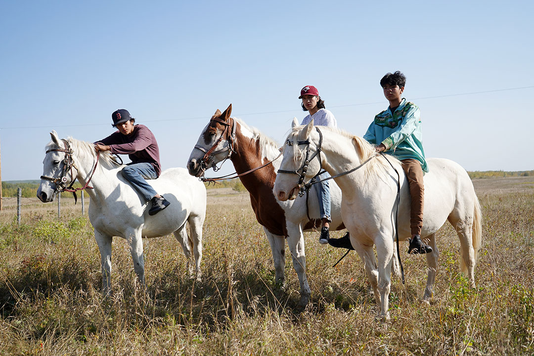 Three young men wait for the Horse Ceremony, an event meant to honour them and help them overcome personal challenges, to begin at Onion Lake Cree Nation. Researchers from Pewaseskwan (the Indigenous Wellness Research Group) at USask are supporting the First Nation to bring back traditional ceremonies. (Photo by Luke Heidebrecht)