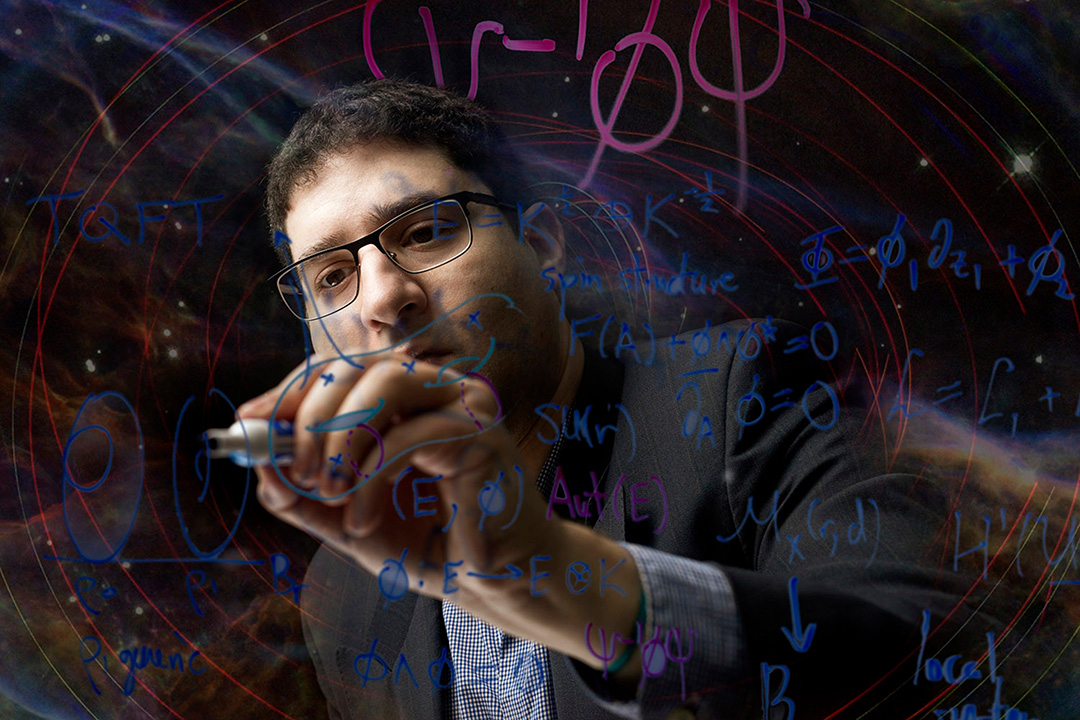 A student writes math equations on a white board in a classroom.