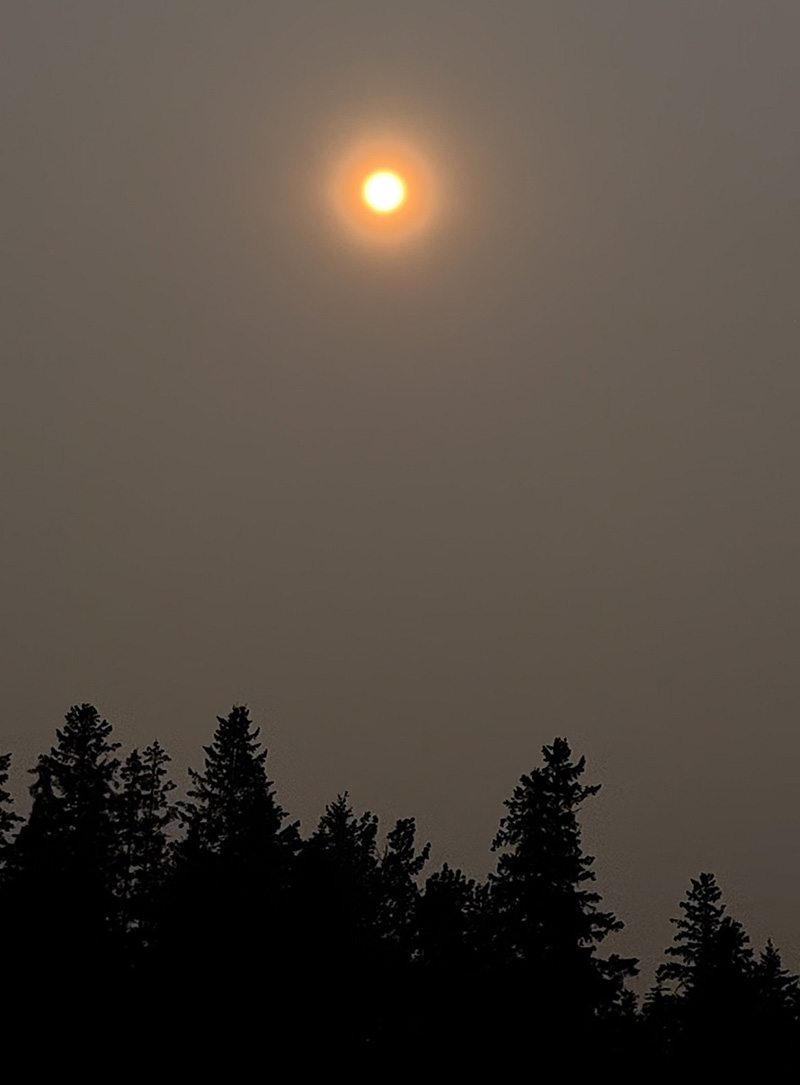 The sun takes on an eerie glow in the sky above the Rocky Mountains, from wildfire smoke along the Alberta-B.C. border. (Photo: Megan Trinidad) 