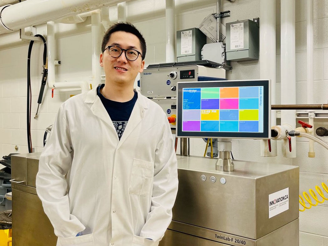 Yikai Ren with the extruder used for producing pet food in the USask Department of Food and Bioproduct Sciences. (Photo: Submitted)