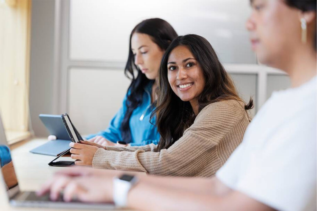 Three students, smiling, with laptop computers