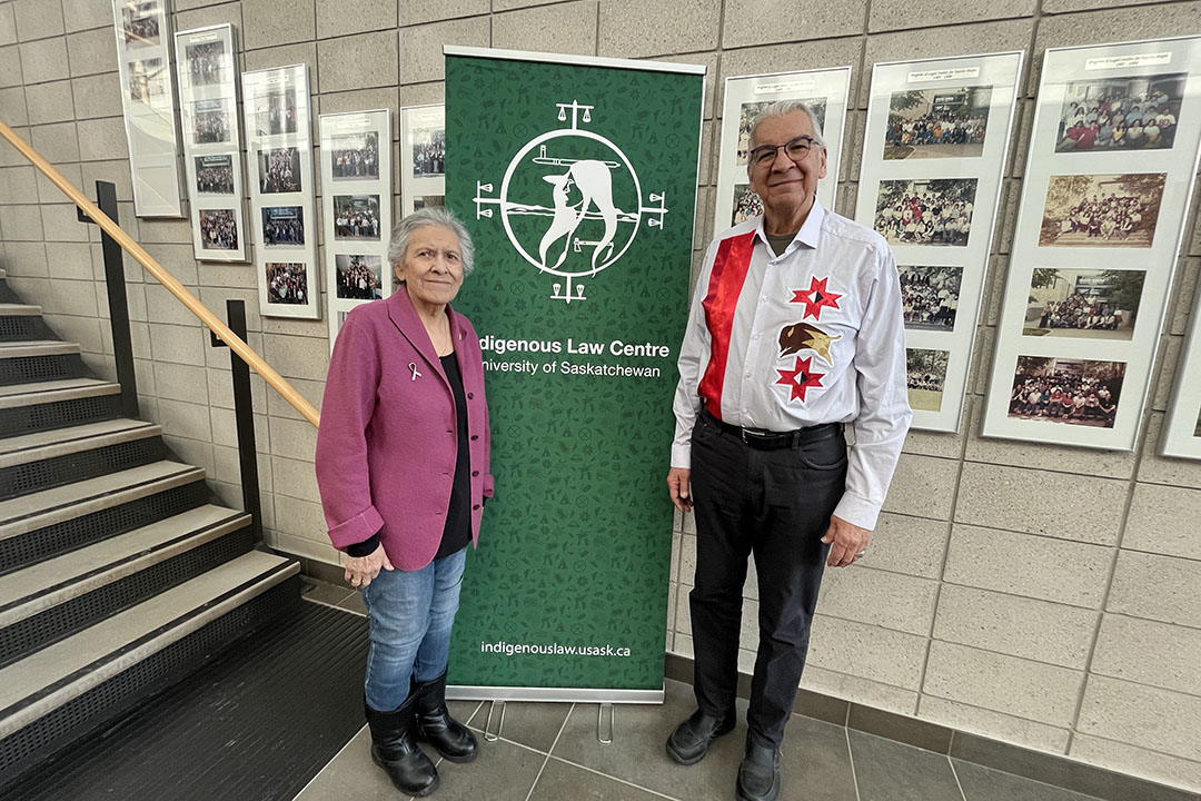 Cultural advisors Julie Pitzel and Joseph Naytowhow outside the Indigenous Law Centre at the University of Saskatchewan, where group photos of summer program graduates are proudly displayed.