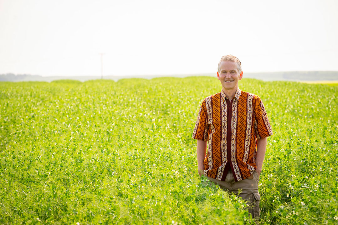 A man standing in a green field, wearing a colourful shirt