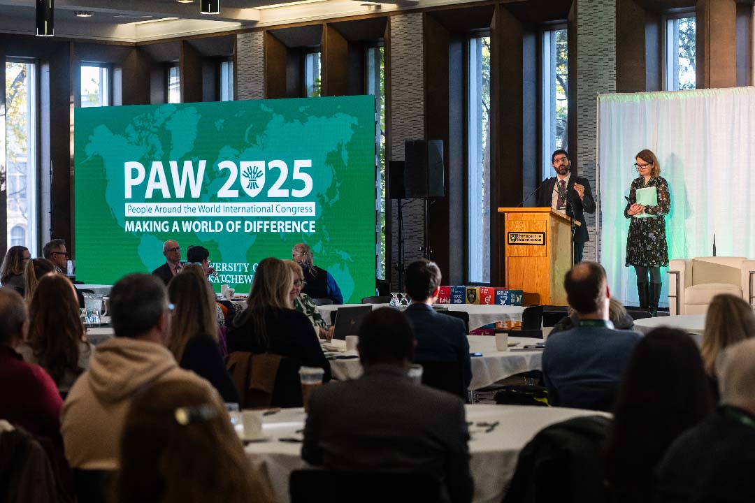 Researchers give a presentation in front of an audience while on stage in a crowded room. 