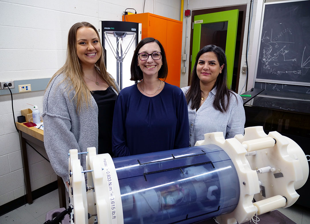 From left: PhD student Kayla Walker, Dr. Emily McWalter (PhD), and Master of Science student Maryam Masoomikhanghah showing off the device their team has developed to test knee models in an MRI machine without interfering metal. (Photo: Matt Olson)